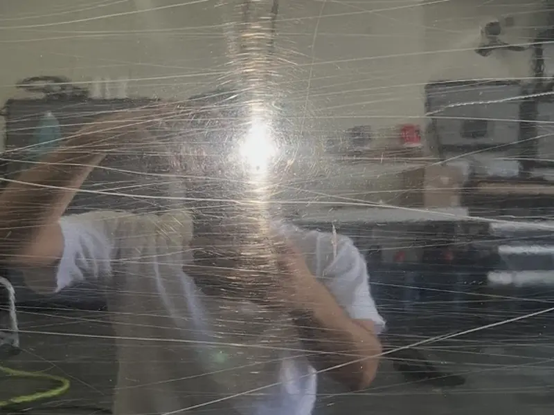 Reflective black panel with heavy scratches before correction